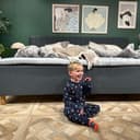 Happy child in pyjamas sitting on the floor in front of a grey family bed