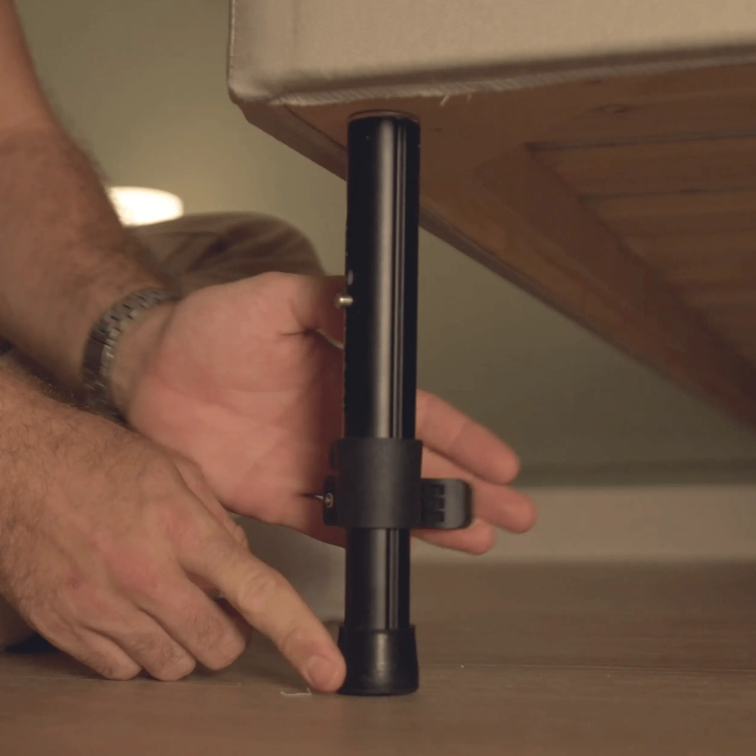 Adjustable aluminium bed leg being fitted beneath a bed