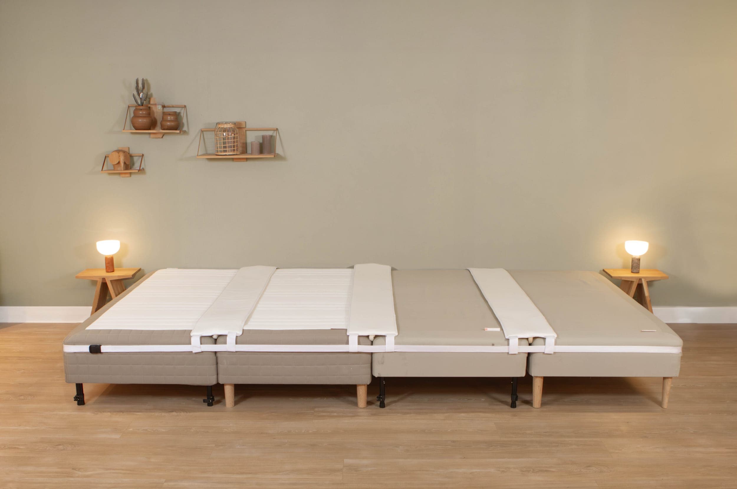 White mattress wedge placed over the join between two mattresses and held in place by the bed strap