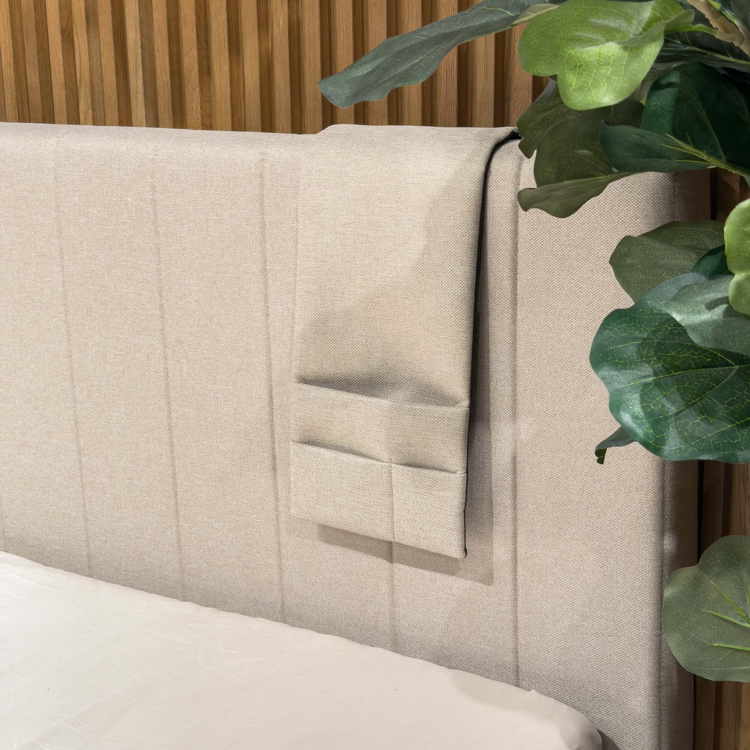 Beige three-compartment bedside pocket hanging over the edge of the headboard