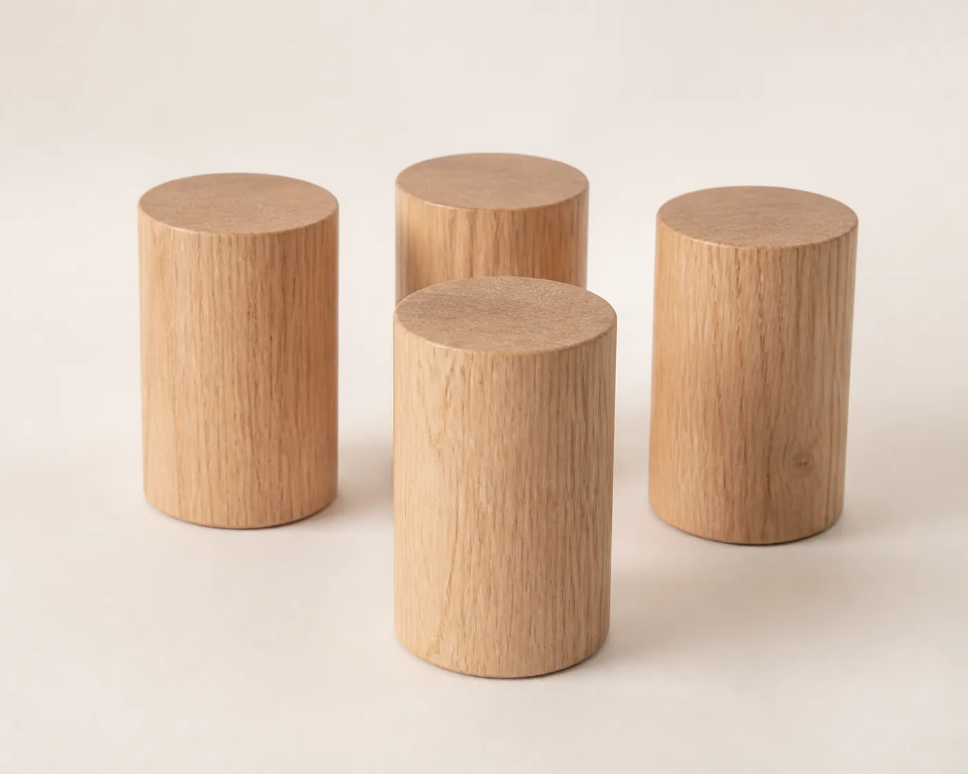 Four cylindrical light-oak bed legs on a pale surface