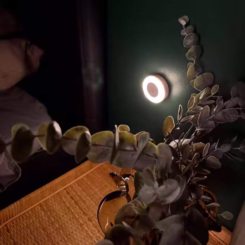 Round breastfeeding light casting a soft glow on the wall beside the bed at night